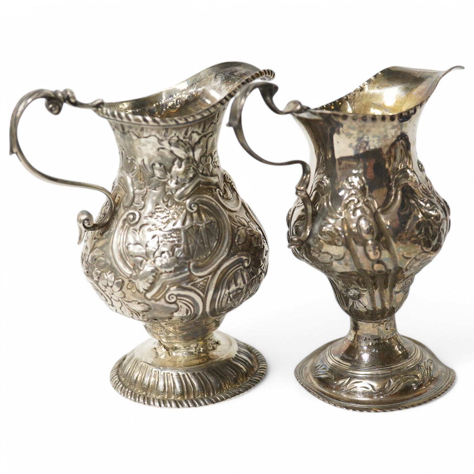 Two Georgian silver cream jugs, with later embossed decoration, inverted pyriform, London, 1782, the other London, 1773 (a.f.). Condition - poor to fair